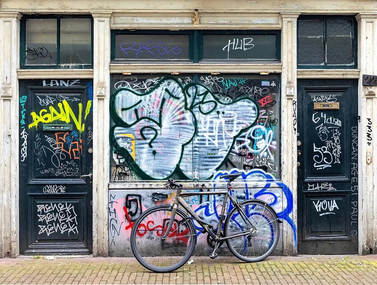 Parked bicycle with graffitied building facade and doors in Amsterdam